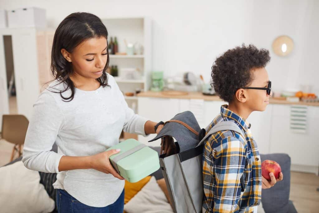 Mom putting a lunch kit in her child's backpack