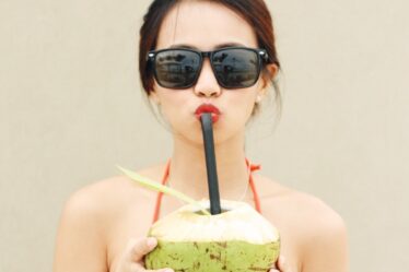 Anything But a Cup Party Ideas featured image of a woman drinking out of a coconut
