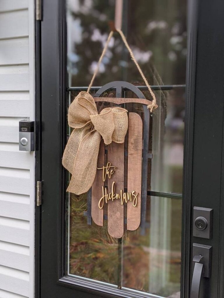 Sleigh wreath hanging on a front door with custom family name as one of the Christmas gift ideas for moms