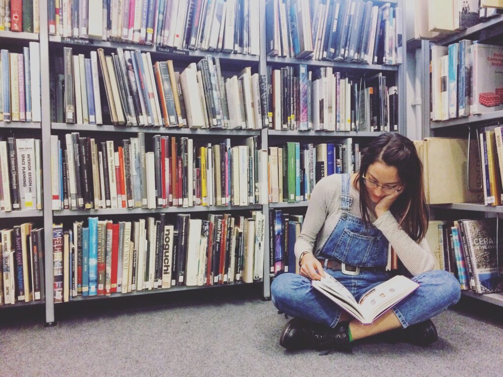 How to Read More Books featured image of a woman reading on the floor of a library