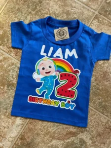 Liam Birthday Boy t-shirt with a Cocomelon character on it, the number 2 in a watermelon print, and a rainbow in the background. The shirt is blue.