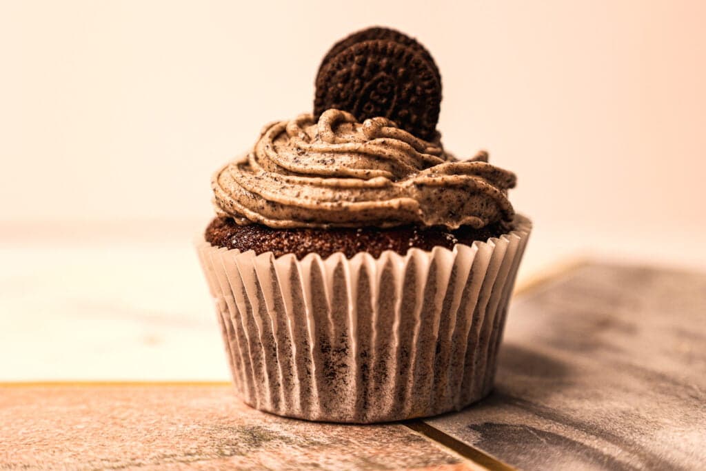 Single Oreo cupcake on a tray - it's decorated with swirly icing and has a mini Oreo on top
