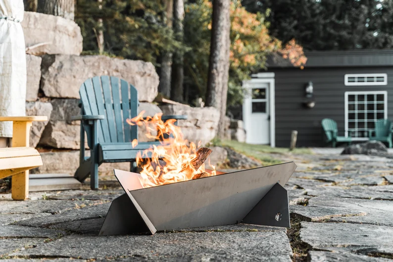 Modern metal fire pit shaped like a triangle and low to the ground