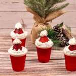 red jello shot with whip cream and strawberries on top that looks like a santa hat