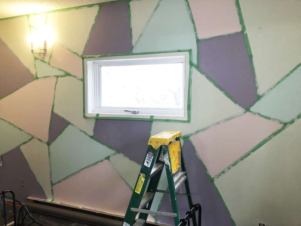 A close up of the accent wall that's been taped off to make geometric shapes and painted with different colours.