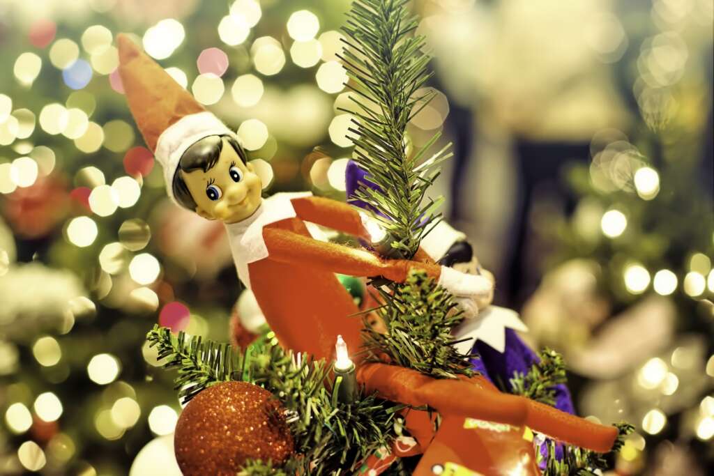 Elf on the shelf hanging from a Christmas tree