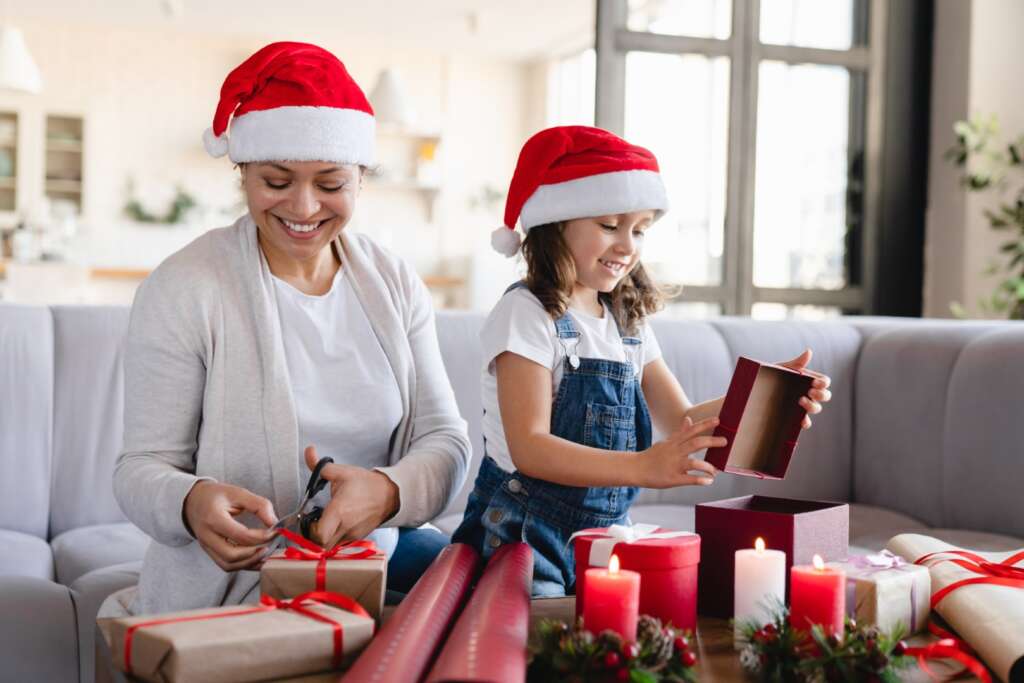 Mom and older kids wrapping Christmas presents together as a holiday tradition