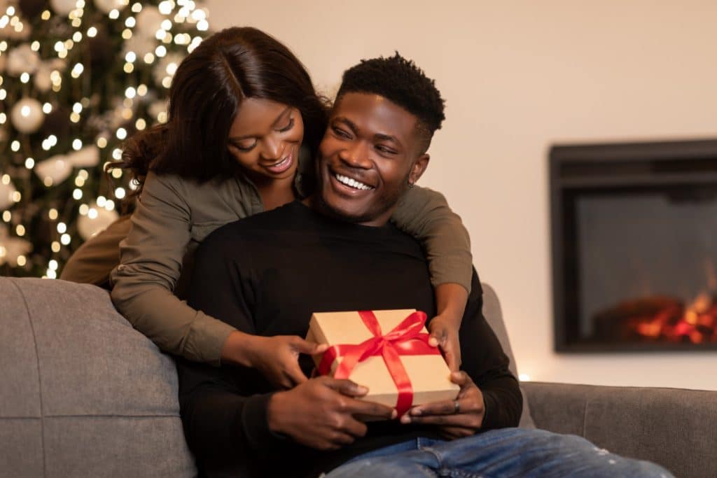 Featured image for Romantic Valentine's Day Gifts for Him That Aren't Cheesy that shows a woman giving a gift to her husband
