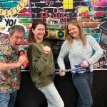 Adult friends taking pictures in front of a photobooth at an 80s themed party