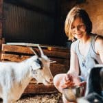Homesteading woman feeding her goat