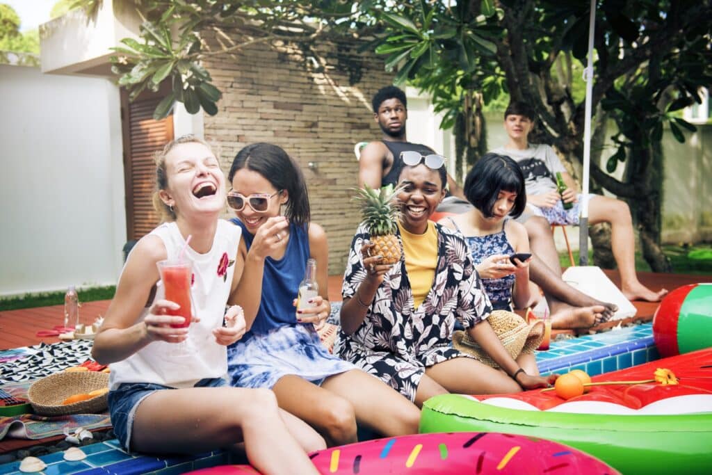 Group of diverse people sitting by the pool with inflatable tubes