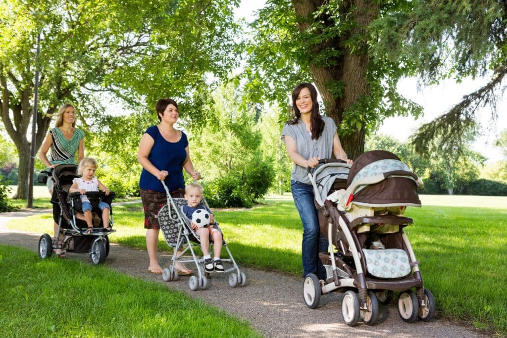 A group of mom friends walking their babies in the park together