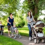 A group of mom friends walking their babies in the park together