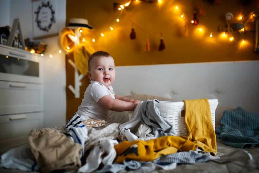 baby playing in the laundry hamper and making a mess
