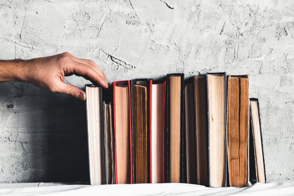Male hand holding a book of bookshelves.