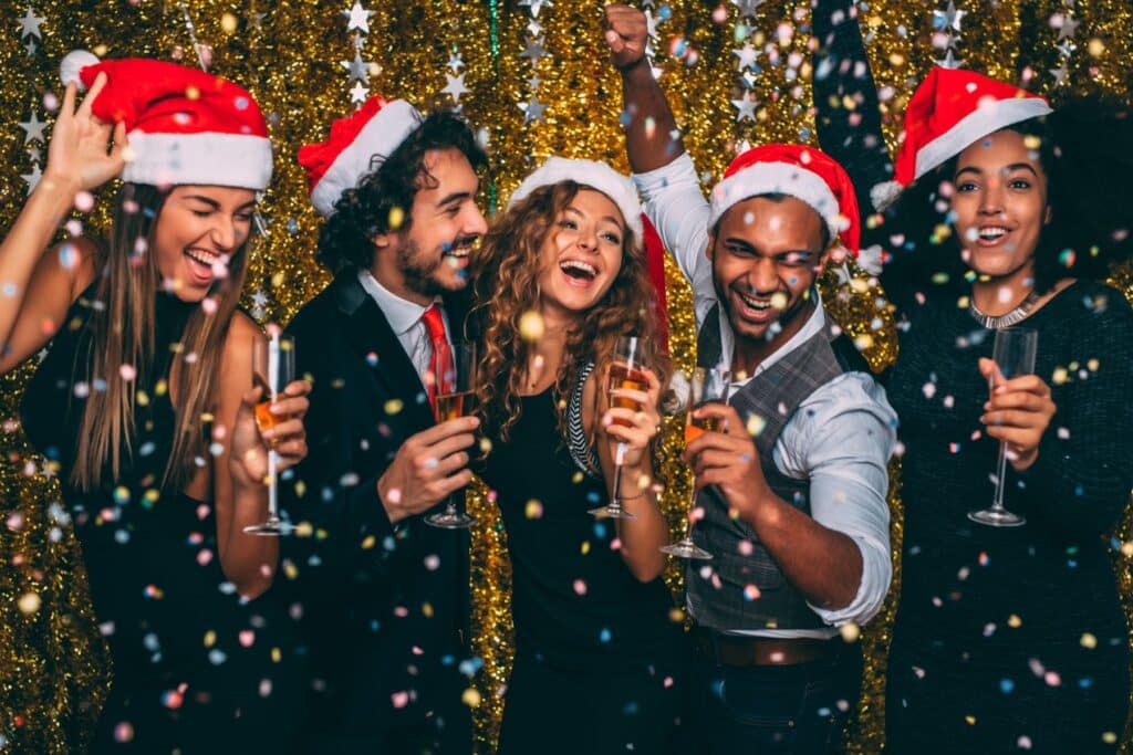 Group of friends having fun at a Christmas party waring Santa hats
