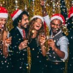 Group of friends having fun at a Christmas party waring Santa hats